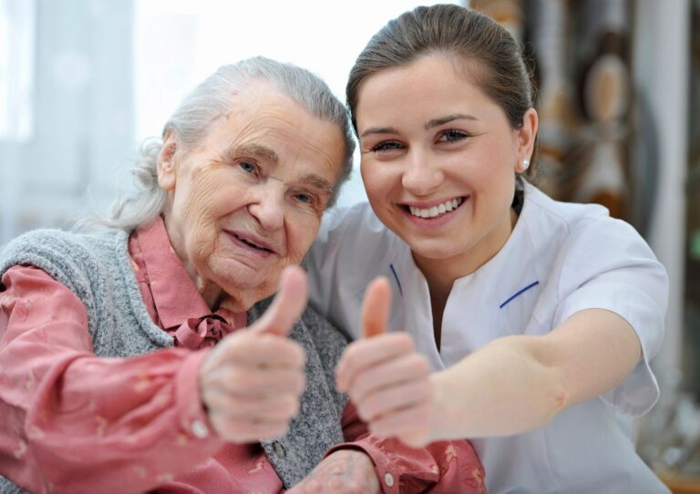 Senior and a nurse holding their thumbs up at our assisted living facility
